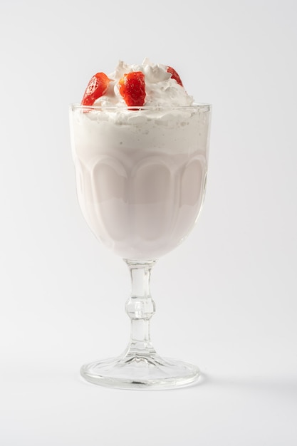 Shake protéiné au lait de fraise, avec de la crème fouettée et du sirop de fraise sur une assiette blanche.