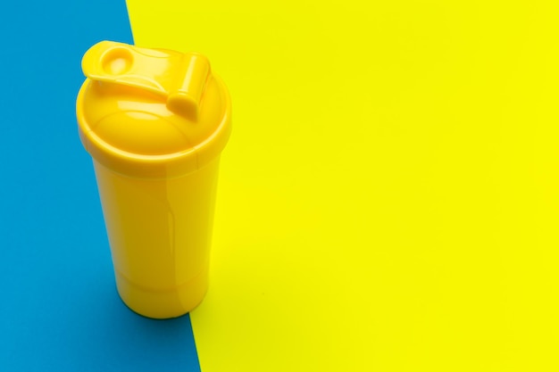 Shaker de protéines en plastique jaune sur fond vibrant