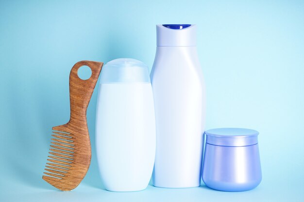 Shampooing, bouteille de revitalisant et brosse à cheveux en bois sur fond bleu