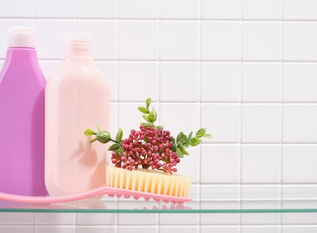 Photo shampooing et pinceau de gel de douche pour le nettoyage de la peau du corps sur un fond de carreaux blancs copier l'espace pour le texte