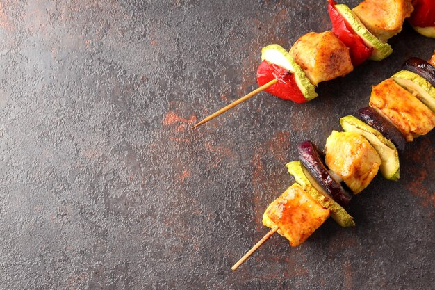 Shashlik de poulet savoureux sur fond texturé sombre