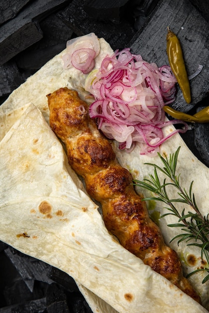 Un shawarma au poulet avec des oignons et des cornichons sur une table