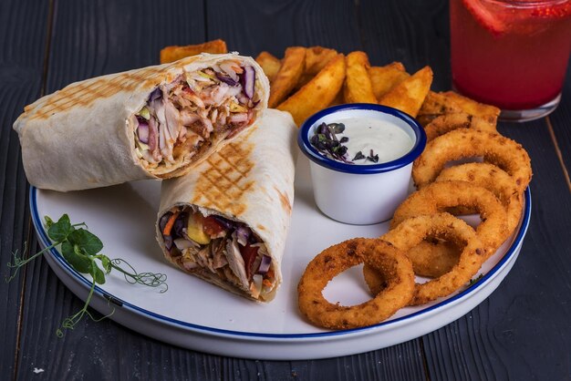 Shawarma et rondelles d'oignon et sauce à l'ail sur un fond en bois noir