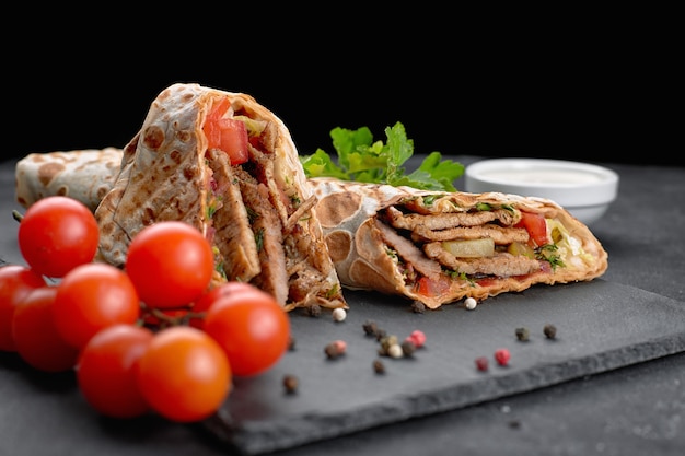 Shawarma à La Viande, Pan Coupé, Avec Sauce, Tomates, Fromage, Herbes Et Ail, Sur Ardoise Noire