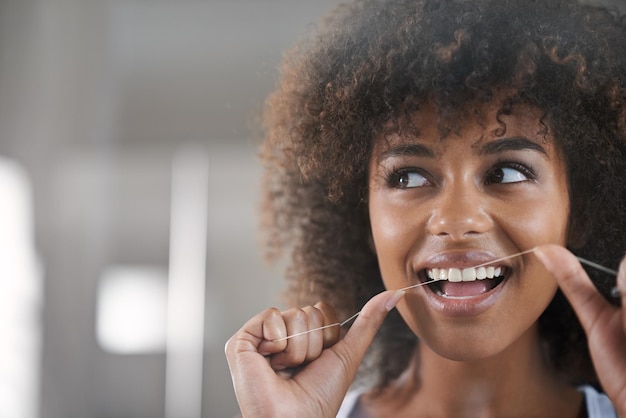 Shes big sur l'hygiène dentaire photo d'une jeune femme passant la soie dentaire dans le miroir