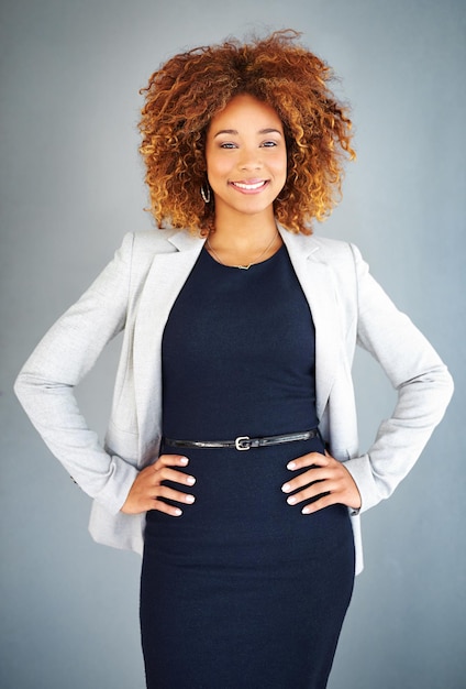 Photo shes portant confiance en soi studio portrait d'une jeune femme d'affaires debout avec ses mains sur ses hanches sur un fond gris