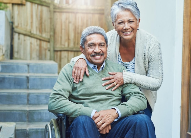 Shes signifie le monde pour moi Portrait d'un vieil homme joyeux assis dans un fauteuil roulant tout en étant tenu par sa femme aimante à l'extérieur à la maison pendant la journée