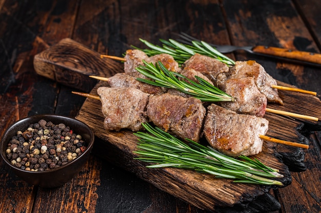 Shish kebab sur des brochettes aux herbes sur une planche de bois