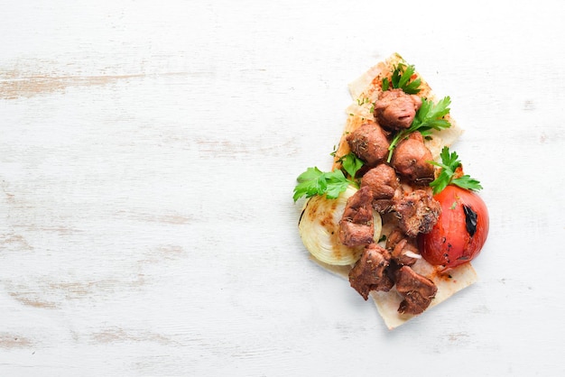 Shish kebab et légumes grillés Sur un fond en bois blanc Vue de dessus