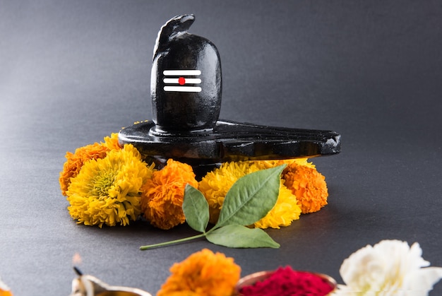 Photo shiva linga décoré de fleurs et bel patra ou feuille et haldi kumkum pour pooja ou adoration de lord shiva ou shankar bhagwan