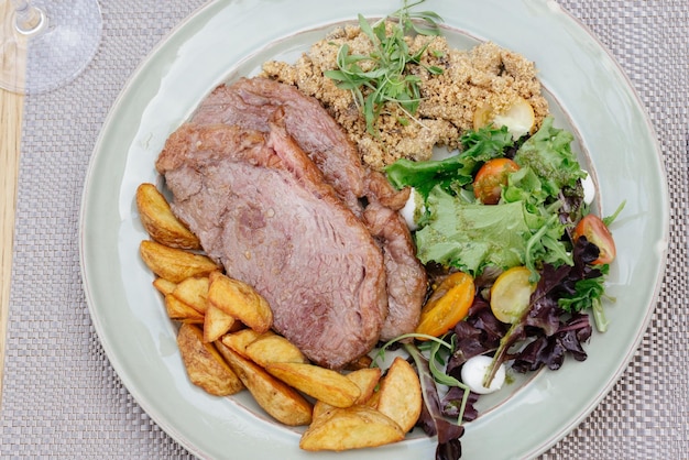 Photo shoot à haut angle de porc grillé avec des légumes verts et des pommes de terre frites