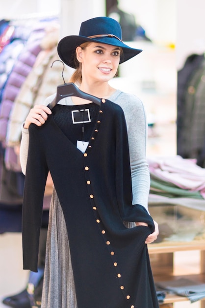 Shopping Belle fille heureuse dans une boutique Essayer une robe et un chapeau