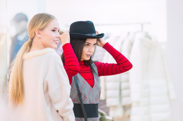 Shopping Belles filles heureuses dans une boutique Essayer des chapeaux de vêtements