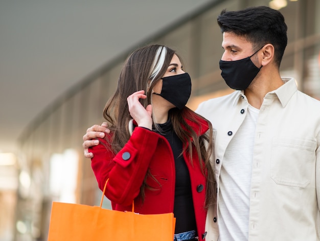 Shopping Covid et coronavirus, jeune couple marchant dans une ville tout en portant des sacs à provisions