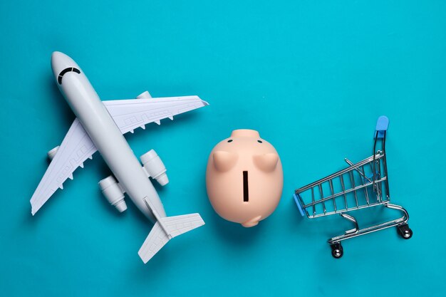 Shopping encore la vie. Caddie, figurine d'avion tirelire sur un bleu