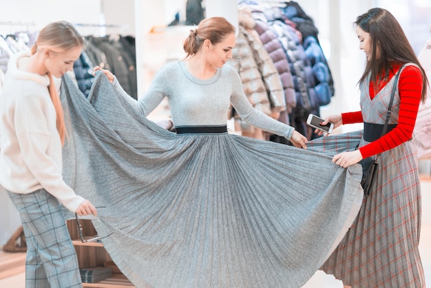 Shopping Groupe de filles heureuses essayant des vêtements dans une boutique