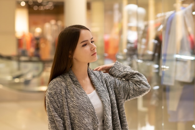 Shopping Une jeune fille regarde les vitrines des magasins, sourit, fait des achats dans un centre commercial.