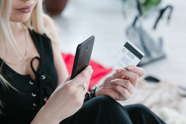 Shopping en ligne. technologie moderne et pratique. paiements mobiles et concept d'achat de marchandises facile. femme tenant le smartphone et la carte de crédit en mains.