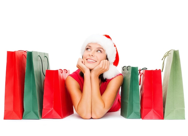 shopping, vente, cadeaux, noël, concept de noël - femme souriante en chemise rouge et bonnet de noel avec des sacs à provisions