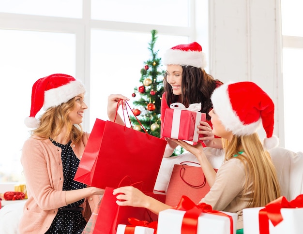 shopping, vente, cadeaux, noël, concept de Noël - femmes souriantes en chapeaux de père Noël avec des sacs à provisions et de nombreux coffrets cadeaux