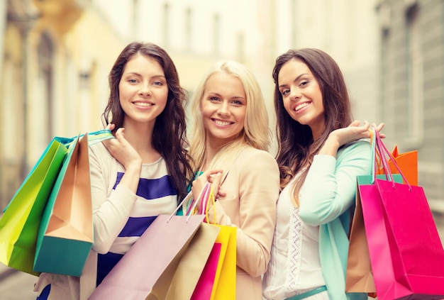 shopping, vente, gens heureux et concept de tourisme - belles filles avec des sacs à provisions en ctiy