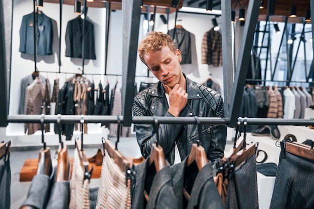 Shopping le week-end Jeune homme dans un magasin moderne avec de nouveaux vêtements Vêtements élégants et chers pour hommes