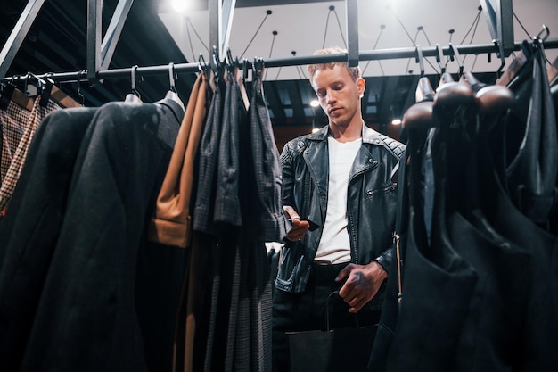 Shopping le week-end Jeune homme dans un magasin moderne avec de nouveaux vêtements Vêtements élégants et chers pour hommes