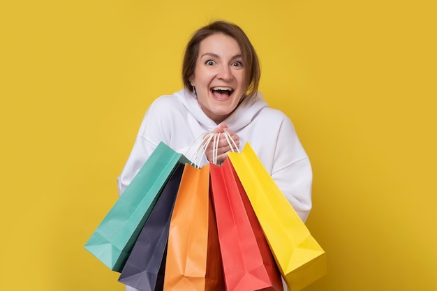 Shopping woman smiling holding shopping bags colorés isolé sur fond jaune Studio shot