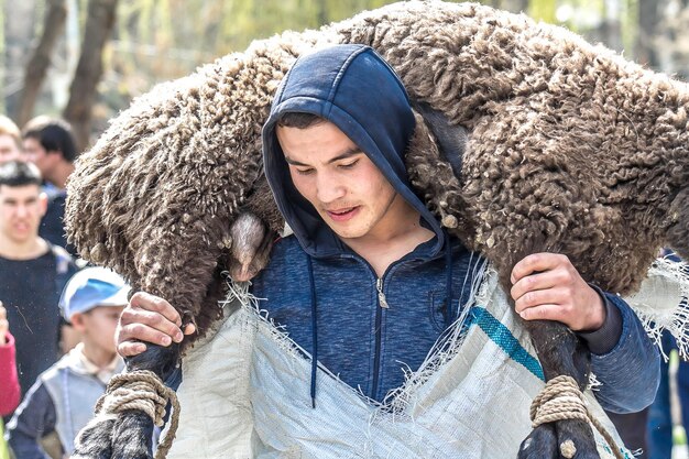 Photo shymkent kazakhstan 20 mars 2018 un homme élève un mouton à la fête de nauryz le jour de l'équinoxe de printemps