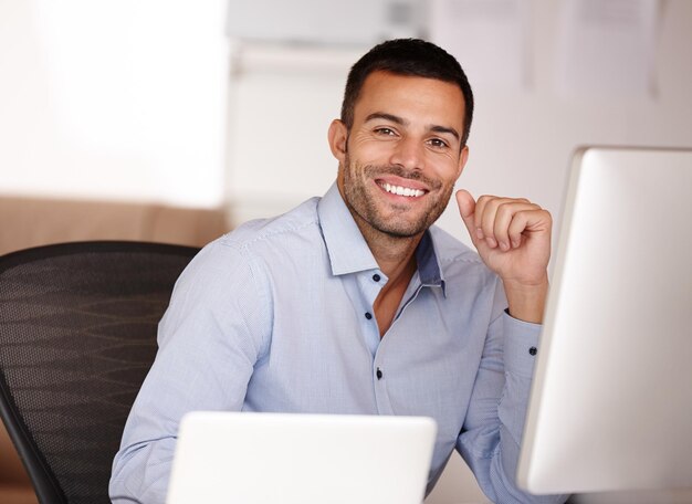 Si vous voulez le meilleur, choisissez-moi Portrait d'un jeune homme souriant assis derrière un écran d'ordinateur