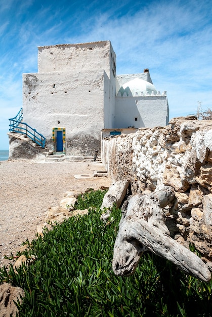 Sidi Kaouki Une vieille bâtisse blanche face à la mer Quelques morceaux de bois mort au premier plan