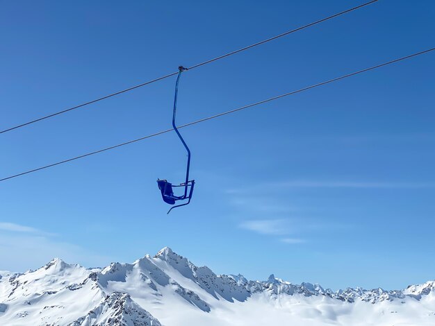 Photo un siège bleu de l'ascenseur de ski dans les montagnes sur un fond de ciel bleu