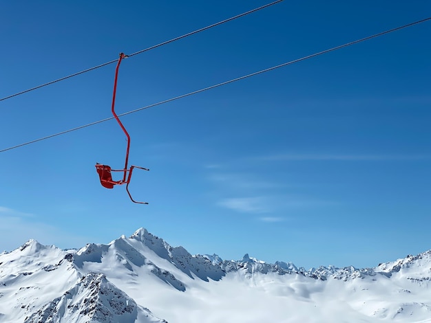 Un siège rouge de l'ascenseur de ski dans les montagnes sur un fond de ciel bleu