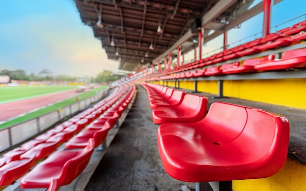 Siège rouge vide sur la tribune pour les fans qui applaudissent au stade de football avec ciel du soir