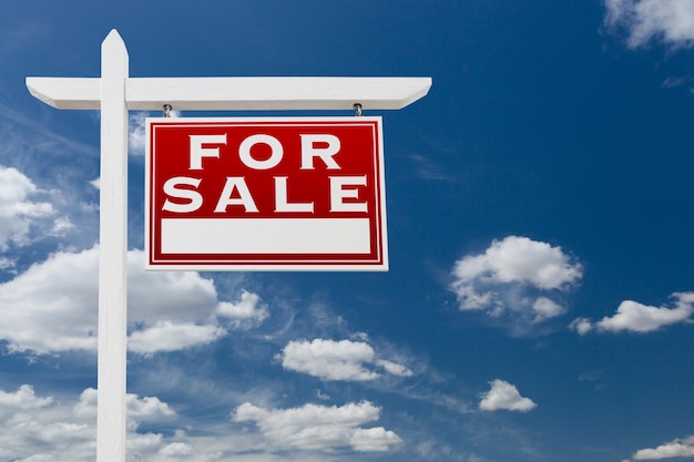 Signage immobilier à vendre au-dessus du ciel bleu et des nuages avec de la place pour votre texte