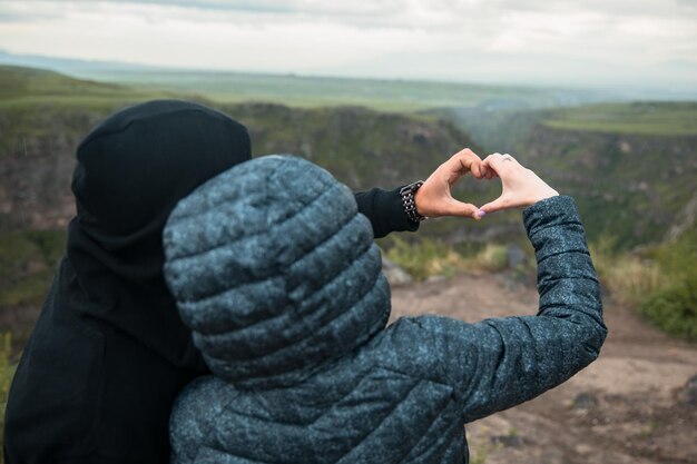 Signe de coeur main femme et homme en montagne