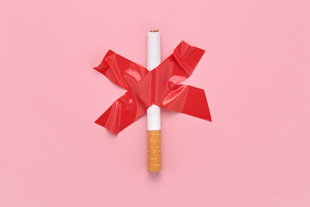 Signe de la croix rouge collé une cigarette, symbole d'interdiction de fumer.