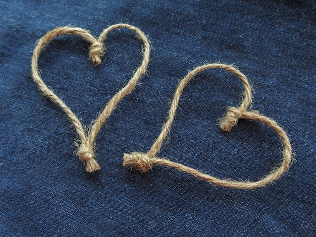 Signe de deux coeurs en ficelle sur denim bleu. Journée mondiale du cœur ou concept d'amour. Fermer