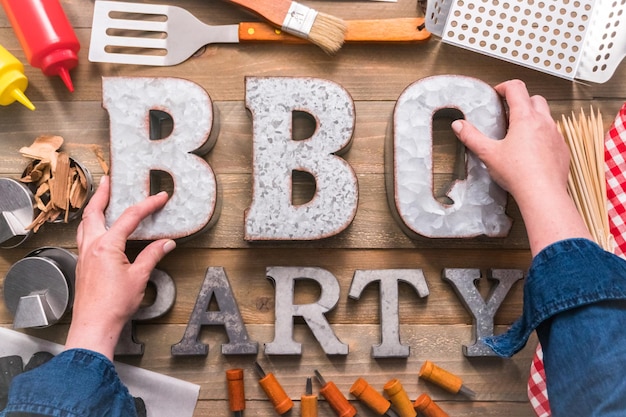 Signe de fête de barbecue en métal avec des outils de grillade sur fond de bois.