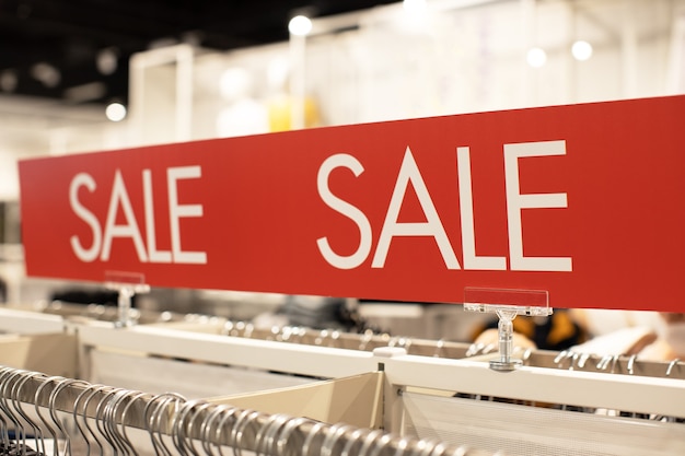 Photo signe avec l'inscription vente en blanc sur fond rouge dans la salle des marchés du magasin de vêtements décontractés