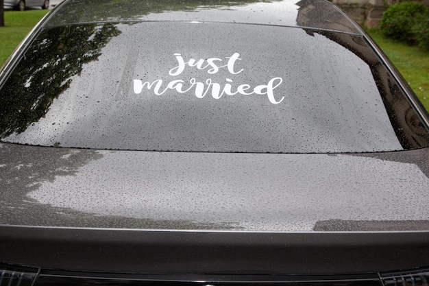 Signe juste marié dans la voiture de vue arrière du jour du mariage pluvieux