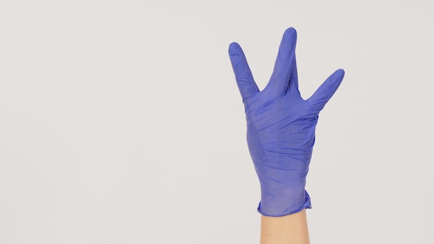 Signe de la main de la côte ouest hiphop et main porter des gants en latex violet ou violet sur fond blanc