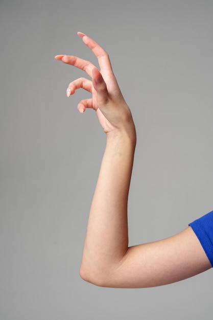 Le signe de la main féminine sur un fond gris dans le studio