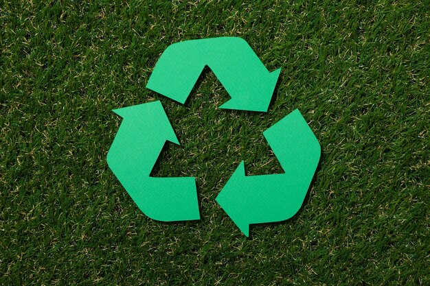 Signe de recyclage de matériaux sur fond d'herbe verte