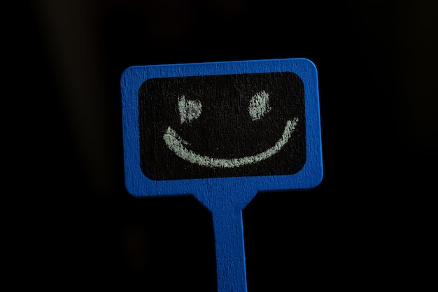 Un signe avec un smiley Affiche en bois bleu avec un sourire positif sur fond noir