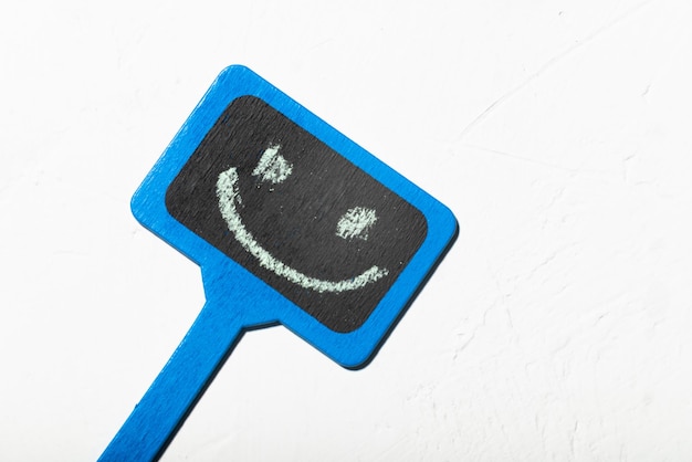 Un signe avec un smiley bleu affiche en bois avec un sourire positif sur un fond blanc