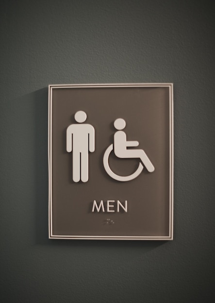 Un signe de toilettes pour hommes a un homme sur un fauteuil roulant.