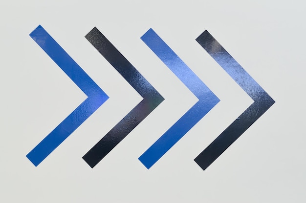 Photo signes d'autocollant de flèche noire et bleue en forme de boomerang sur le mur pointant vers le côté droit toile de fond ou arrière-plan de symbole d'art peint coloré