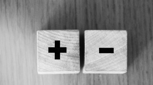 Signes plus et moins sur des cubes en bois sur une table en bois Concept de solution d'entreprise