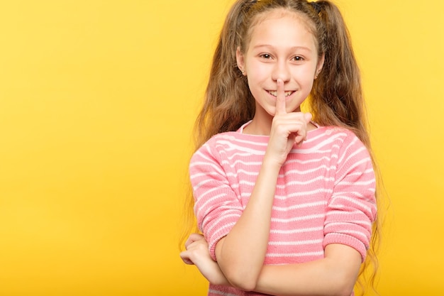 Silence et calme. petite fille faisant taire le spectateur. doigt sur les lèvres. expression faciale.